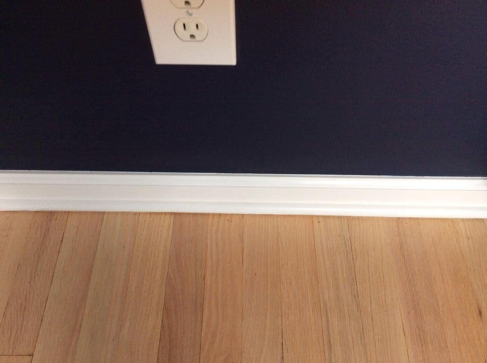 Close-up of wood floor edging against a dark blue wall