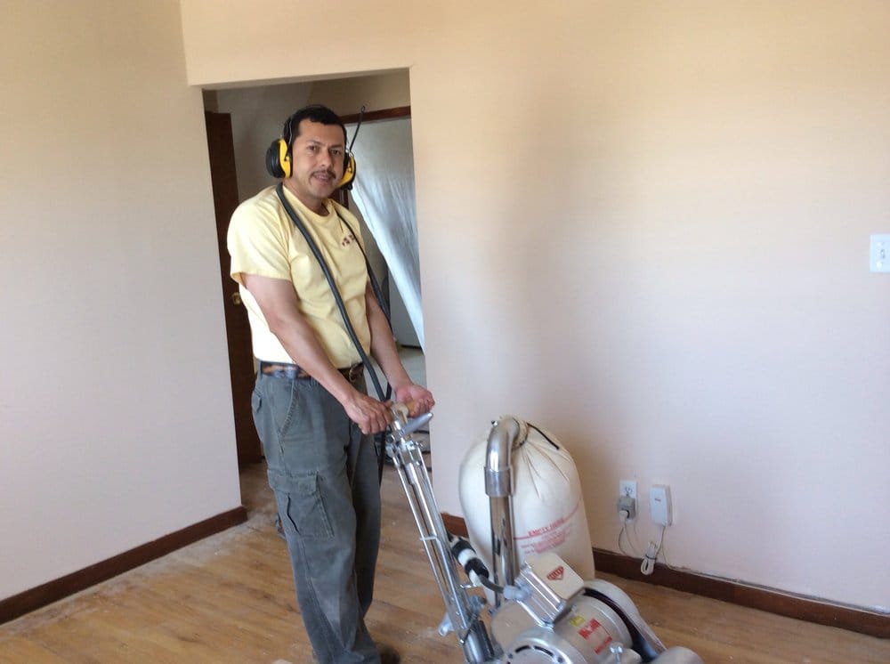 Worker buffing a hardwood floor before finishing